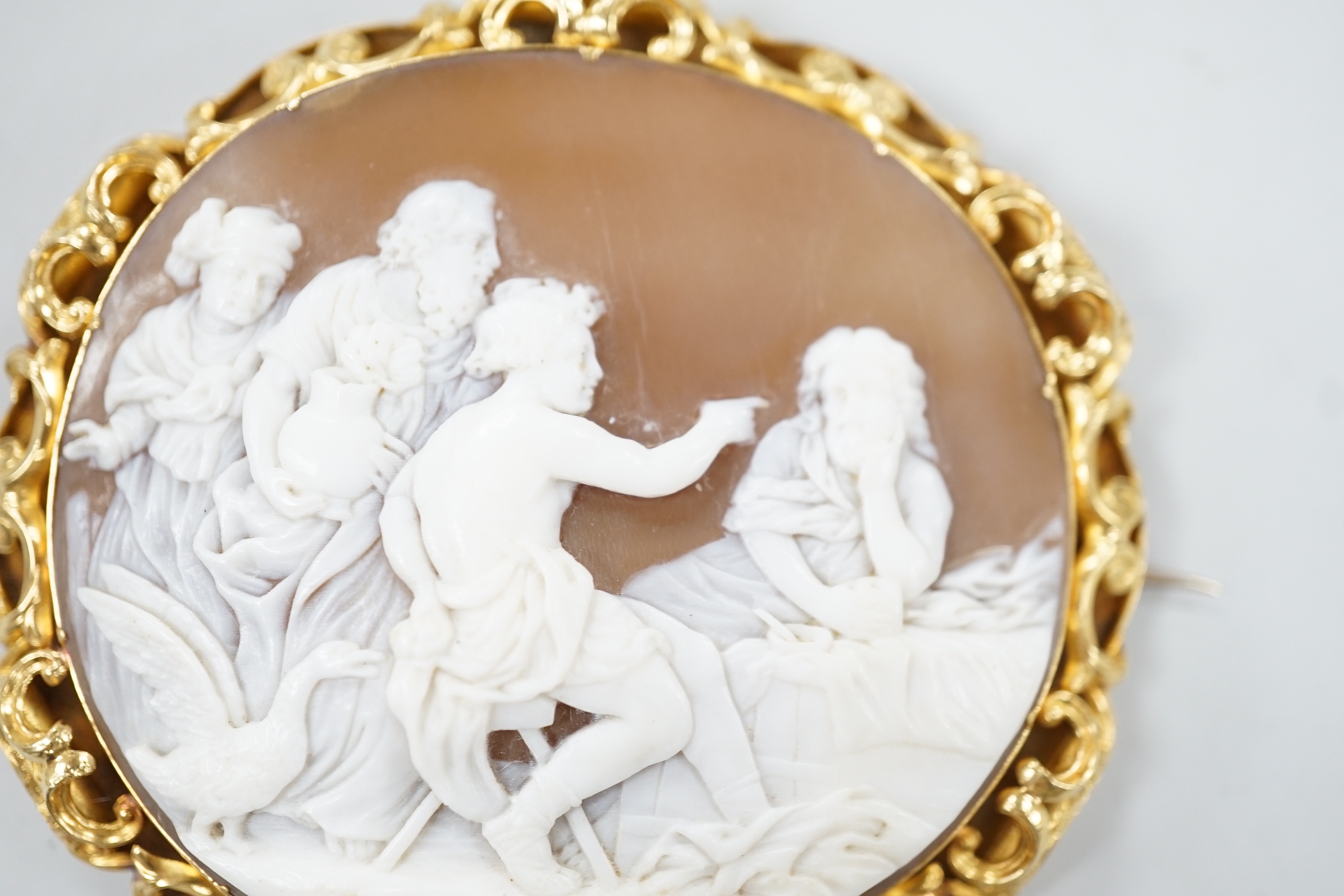 A Victorian yellow metal mounted oval cameo shell brooch, carved with classical figures, width 64mm, gross weight 26.8 grams (pin clasp a.f.).